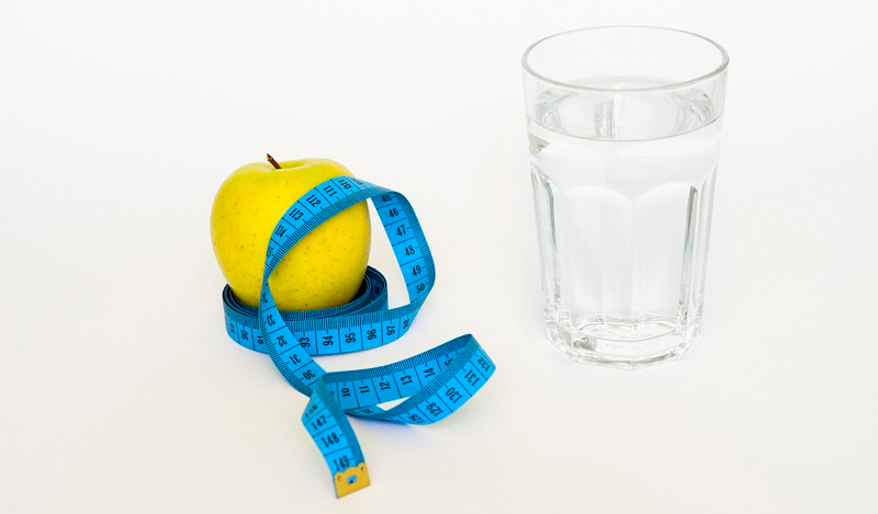 Image of a measuring tape, apple and glass of water